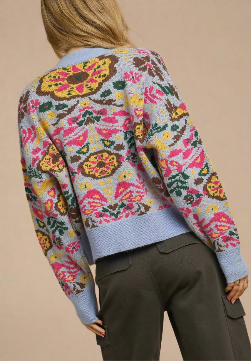 Person wearing a colorful patterned sweater with a beige background