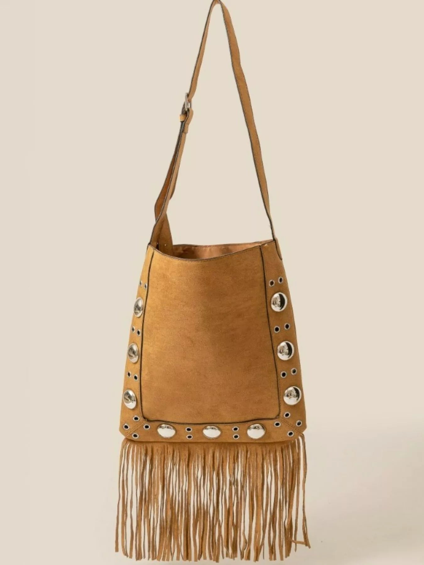 Brown suede handbag with fringe and grommet details on a beige background