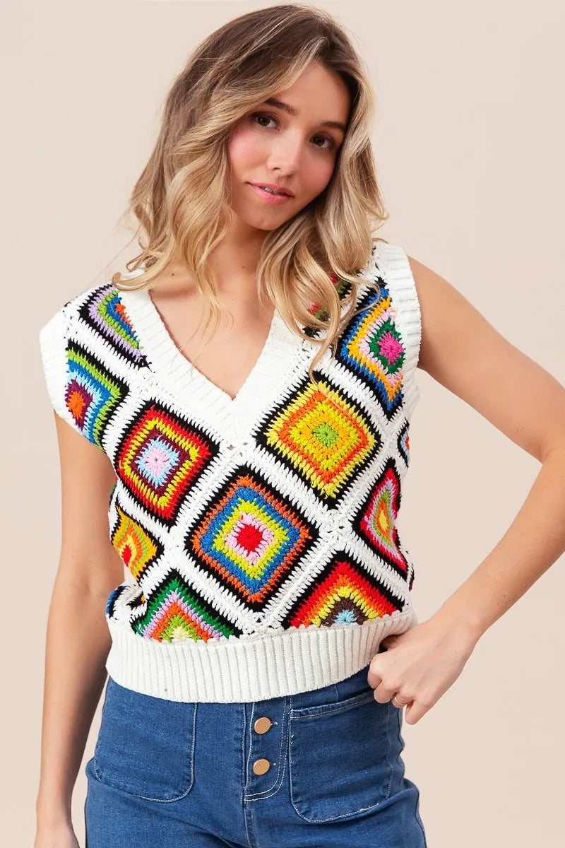 Woman wearing a colorful patterned sleeveless sweater against a beige background