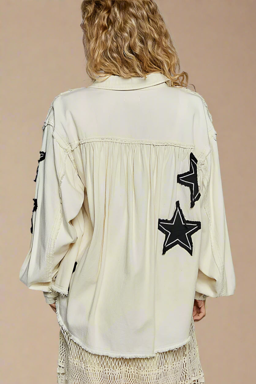 Person wearing a beige jacket with black star patches on a plain background