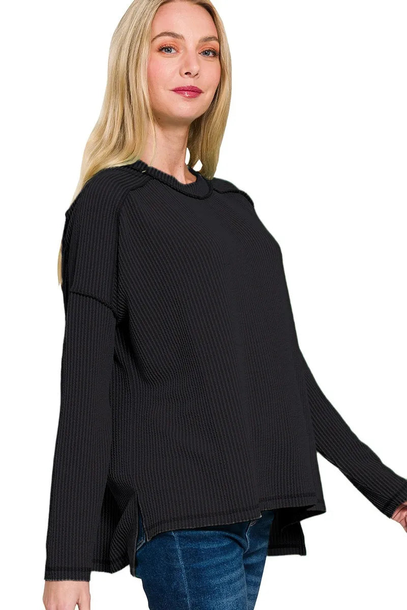 Woman wearing a black ribbed sweater with a white background