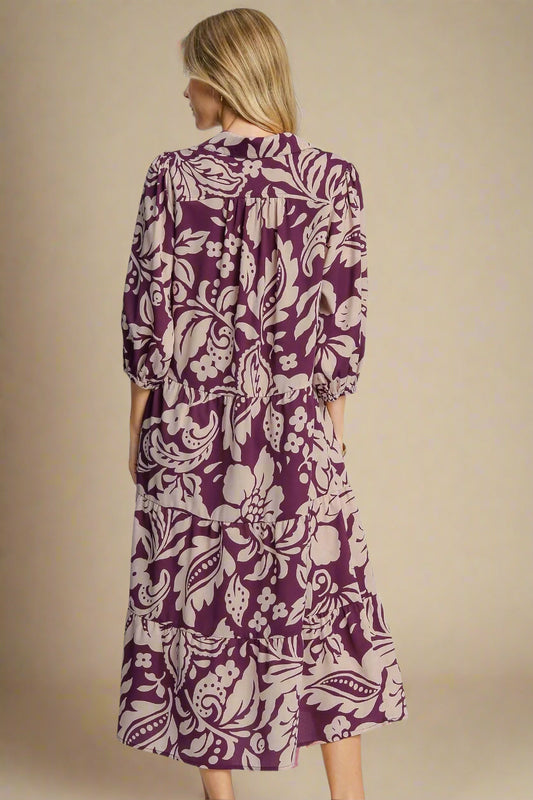 Woman wearing a purple floral dress on a plain background