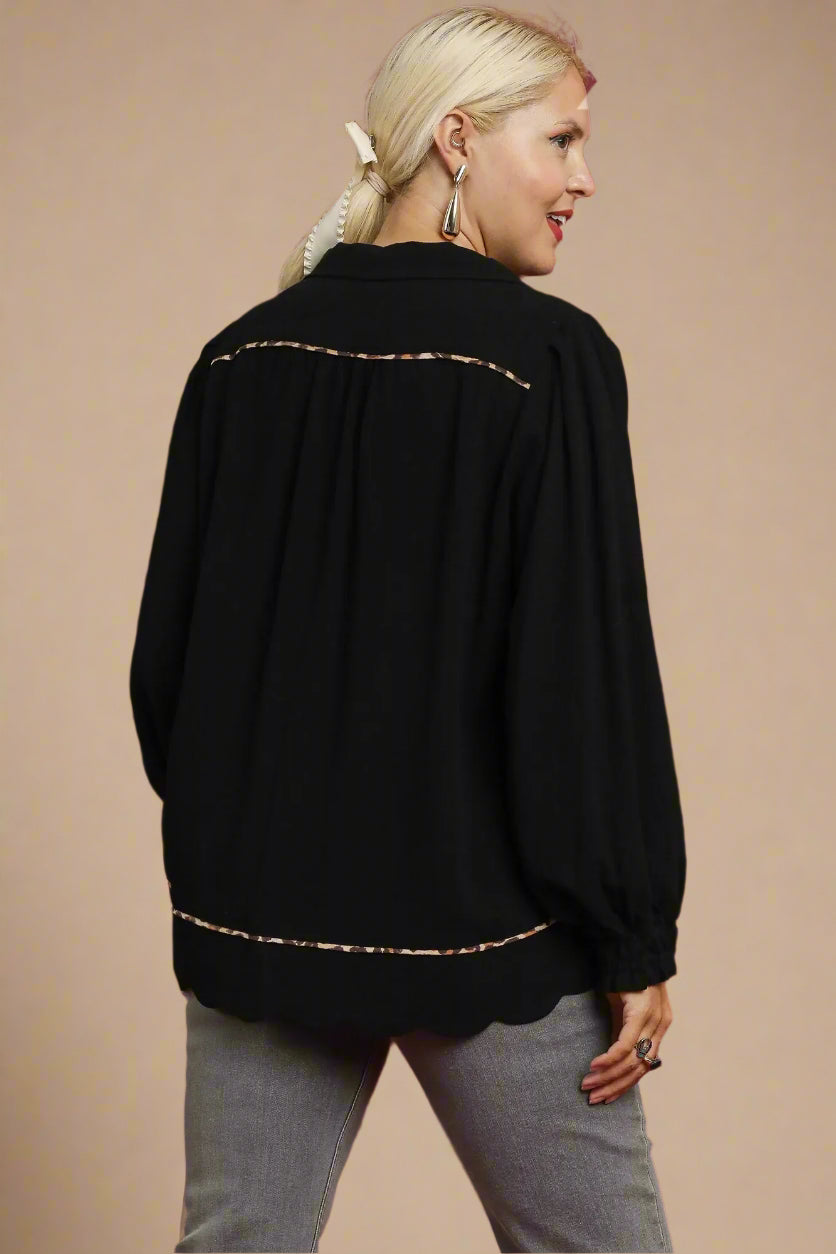 Woman wearing a black top with leopard trim on a beige background