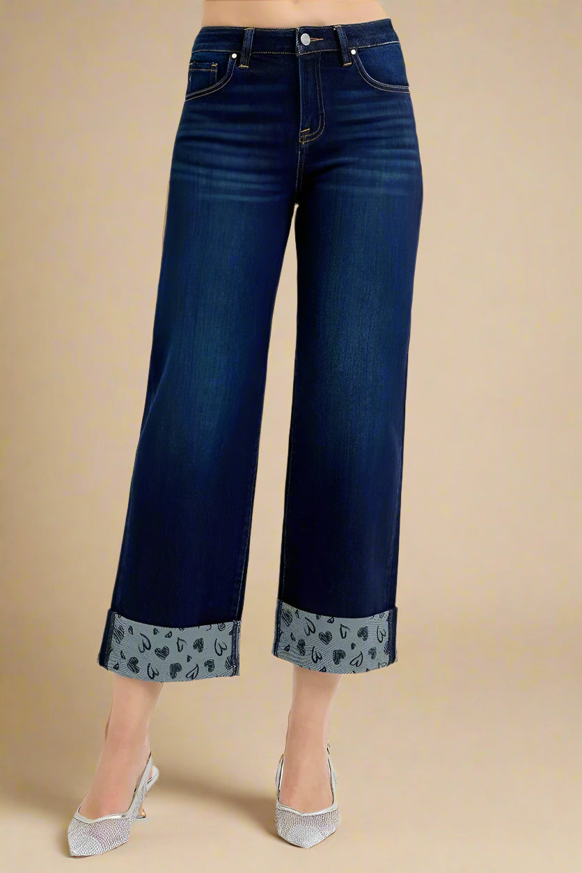 Dark blue jeans with heart print cuffs on a white background