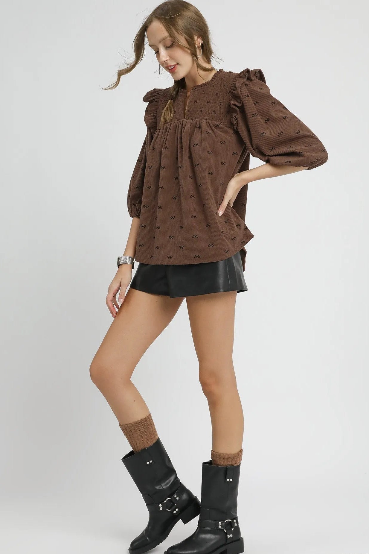 Woman wearing a brown blouse with puff sleeves and a black skirt on a white background