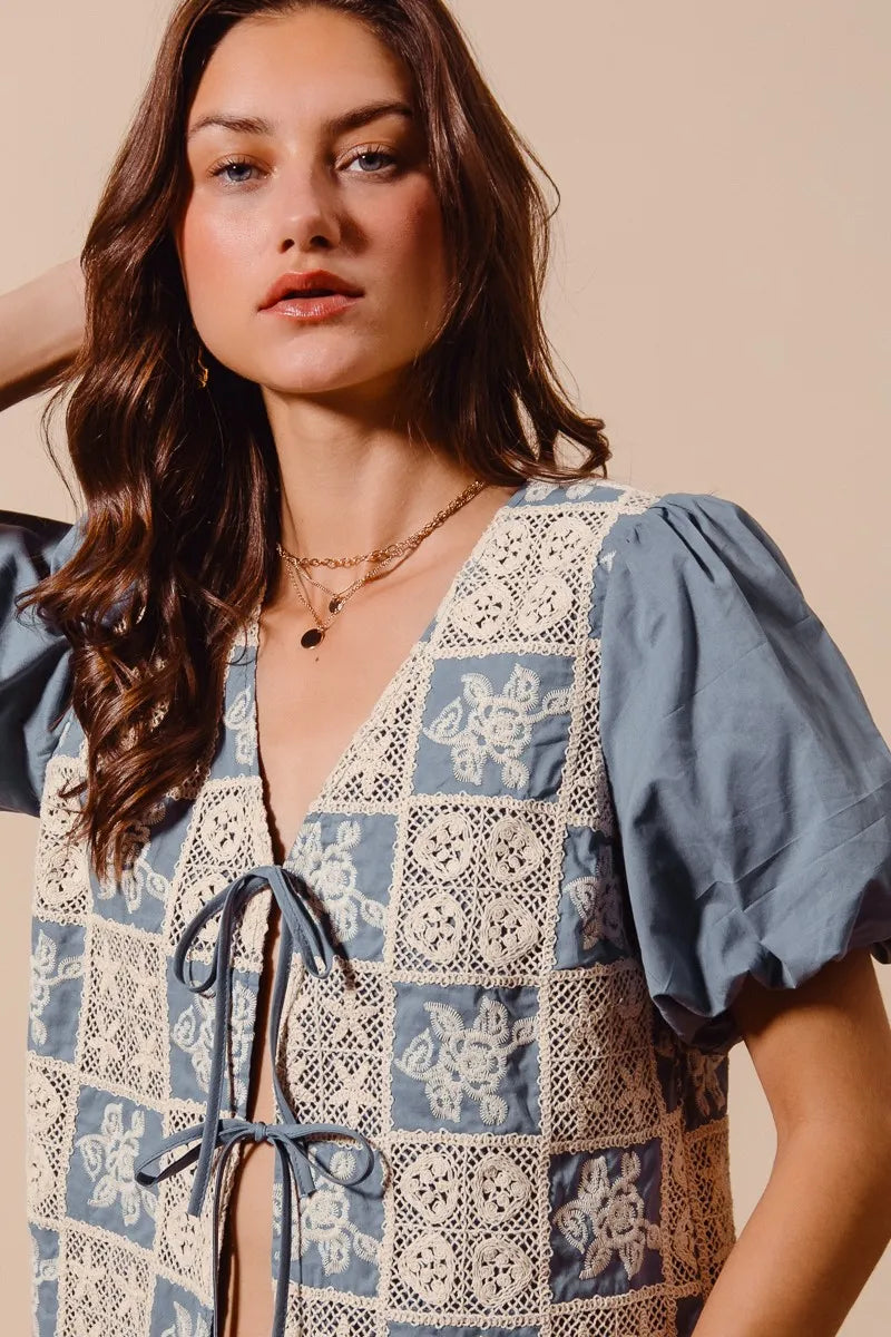 Woman wearing a patterned top with blue and white design on a beige background