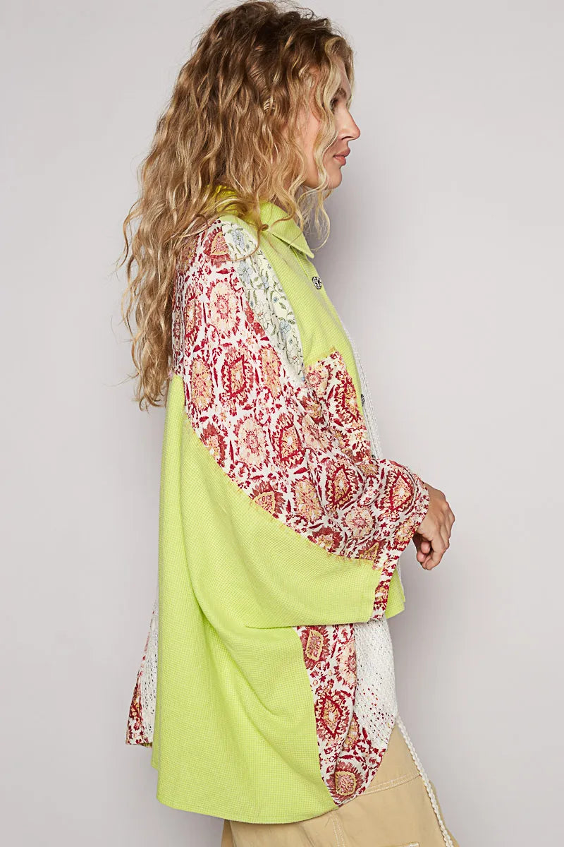 Woman wearing a bright green shirt with red and white patterned sleeves against a plain background