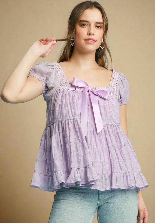 Woman wearing a lavender blouse with a bow tie on a beige background