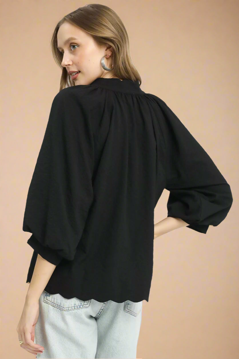 Woman wearing a black blouse with balloon sleeves on a white background