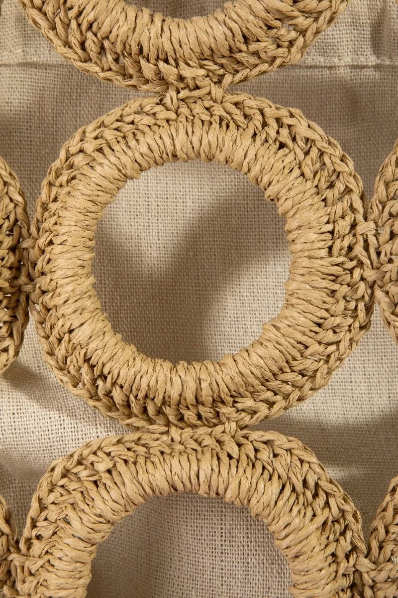 Close-up of woven circular patterns on a textured beige background