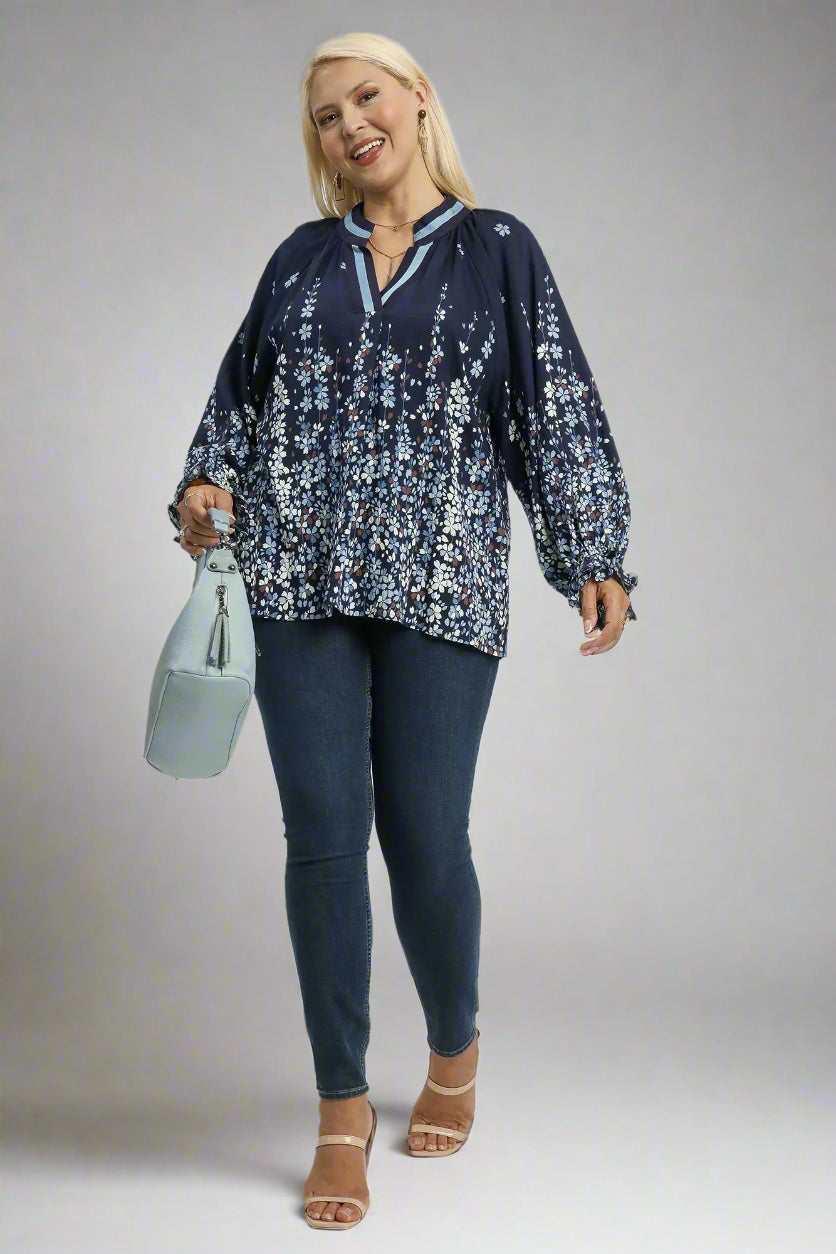 Woman wearing a navy floral blouse and dark jeans on a white background