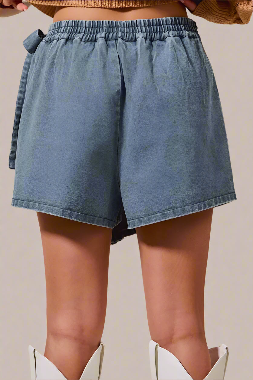 Blue denim shorts worn by a person on a beige background