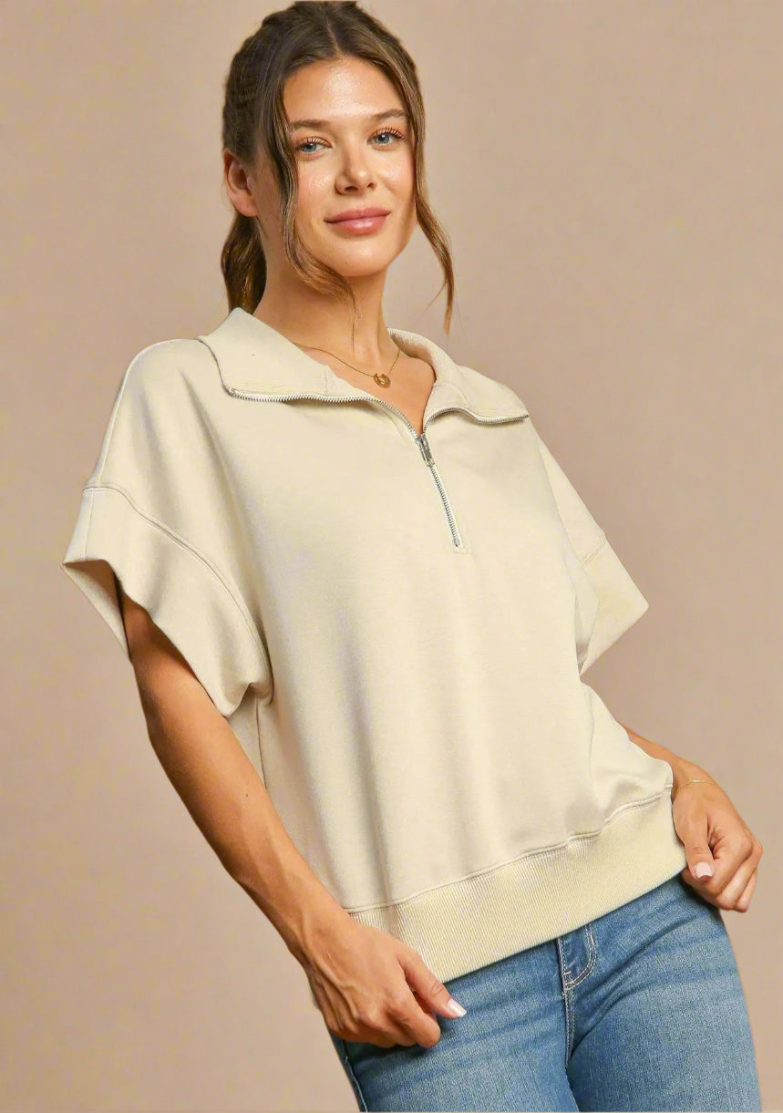 Woman wearing a beige top and blue jeans against a brown background