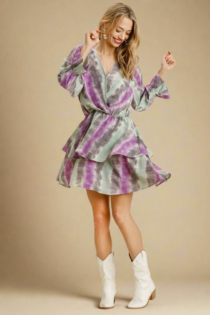 Woman wearing a green and purple tie-dye dress with white boots on a beige background