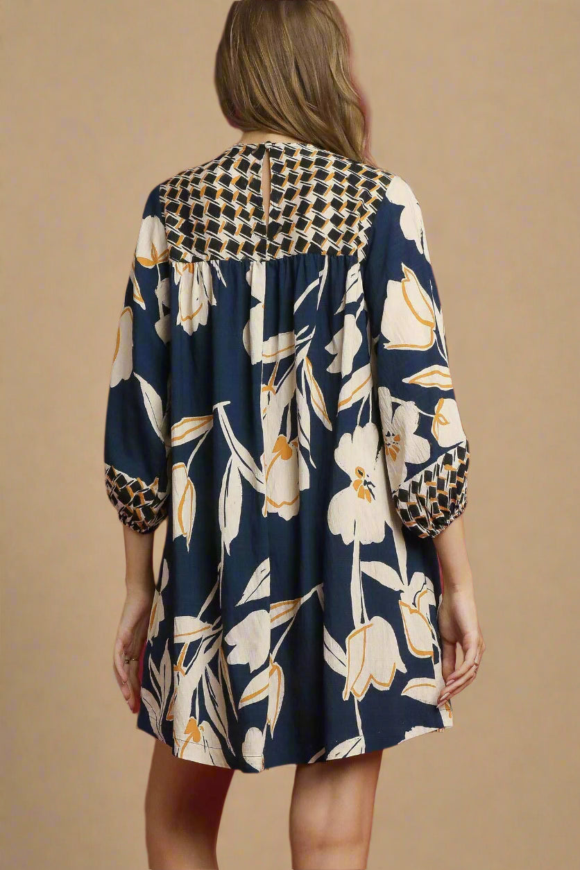 Woman wearing a floral dress with a houndstooth pattern on a red background