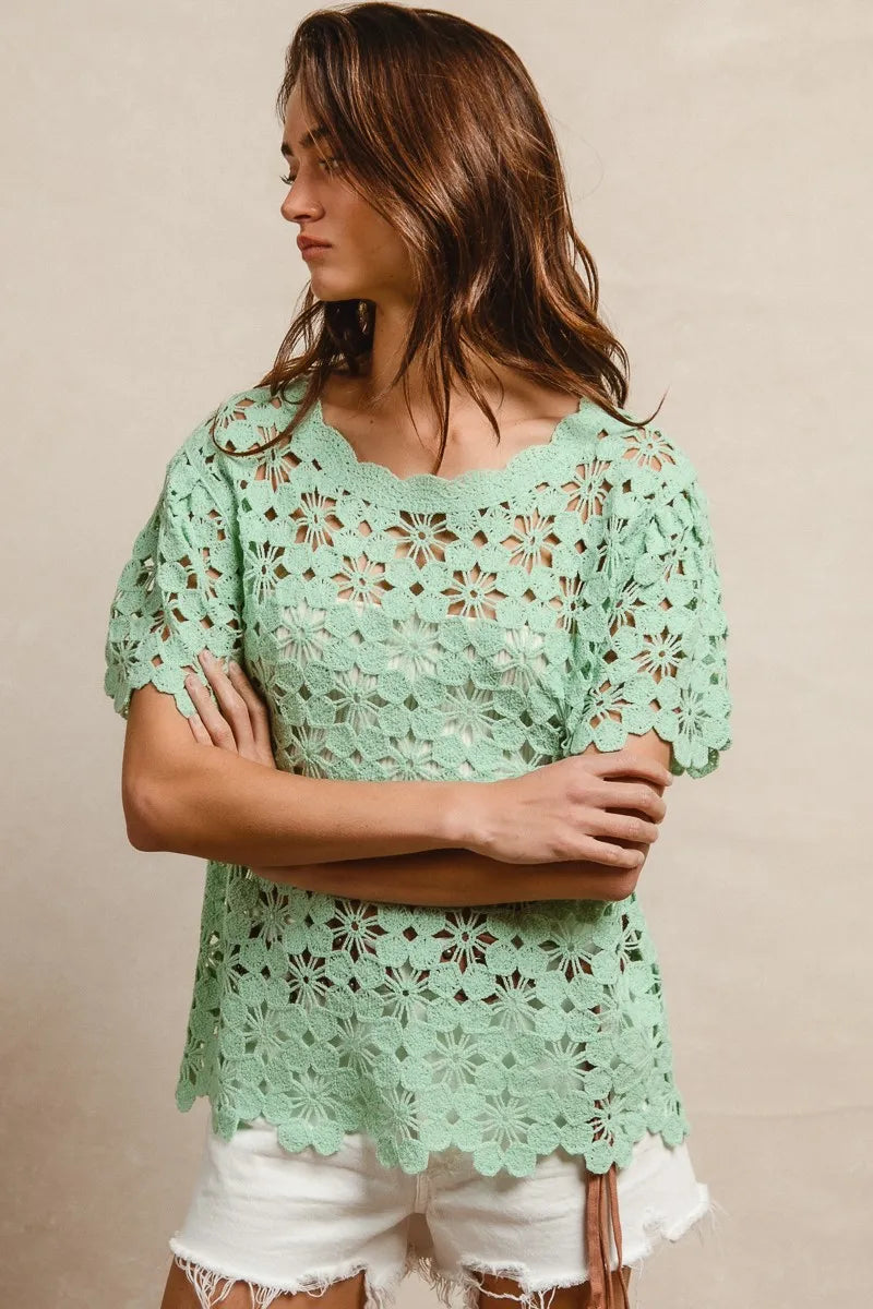 Woman wearing a light green lace top against a beige background