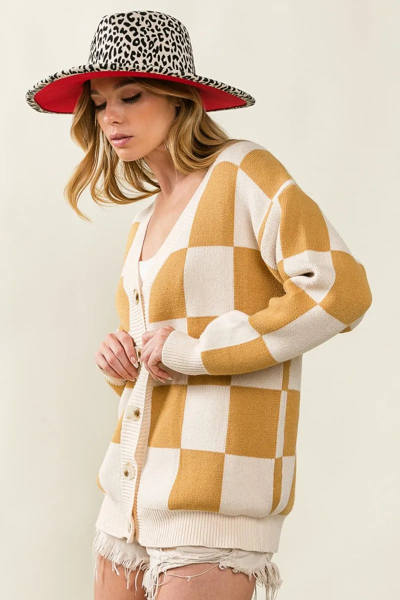 Woman wearing a checkered cardigan and leopard print hat on a plain background