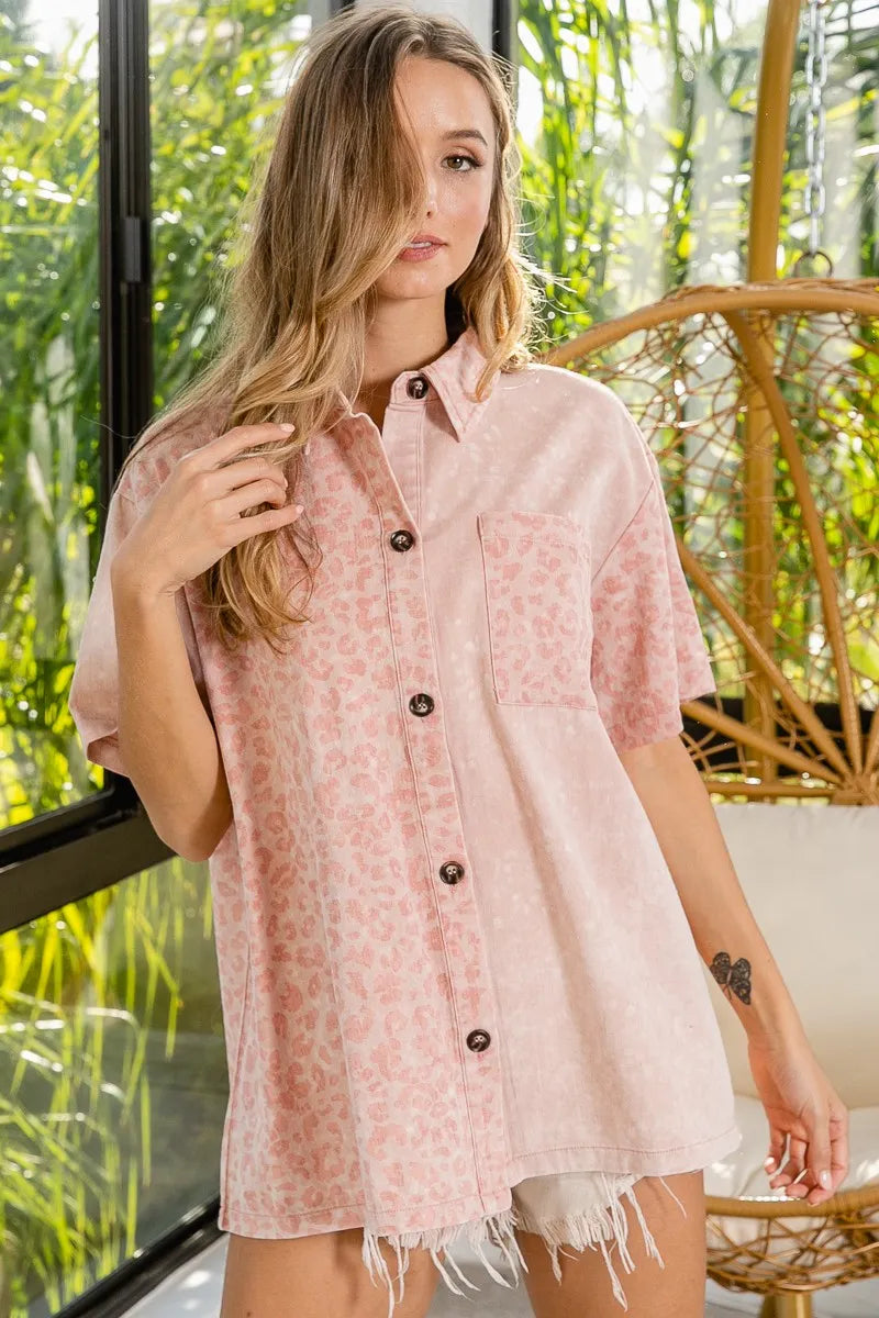 Woman wearing a light pink floral shirt with black buttons in an outdoor setting.