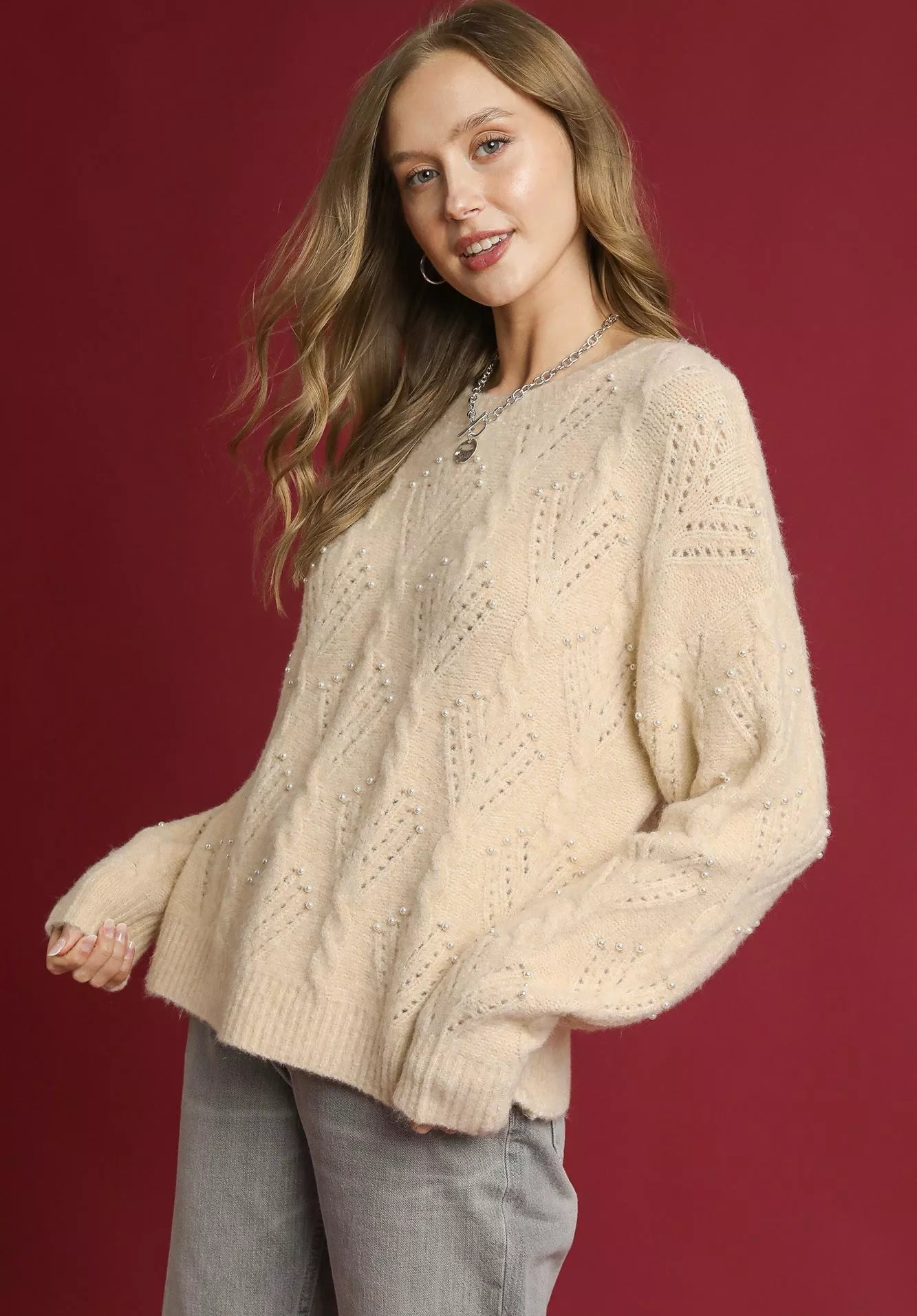 Woman wearing a cream sweater against a red background