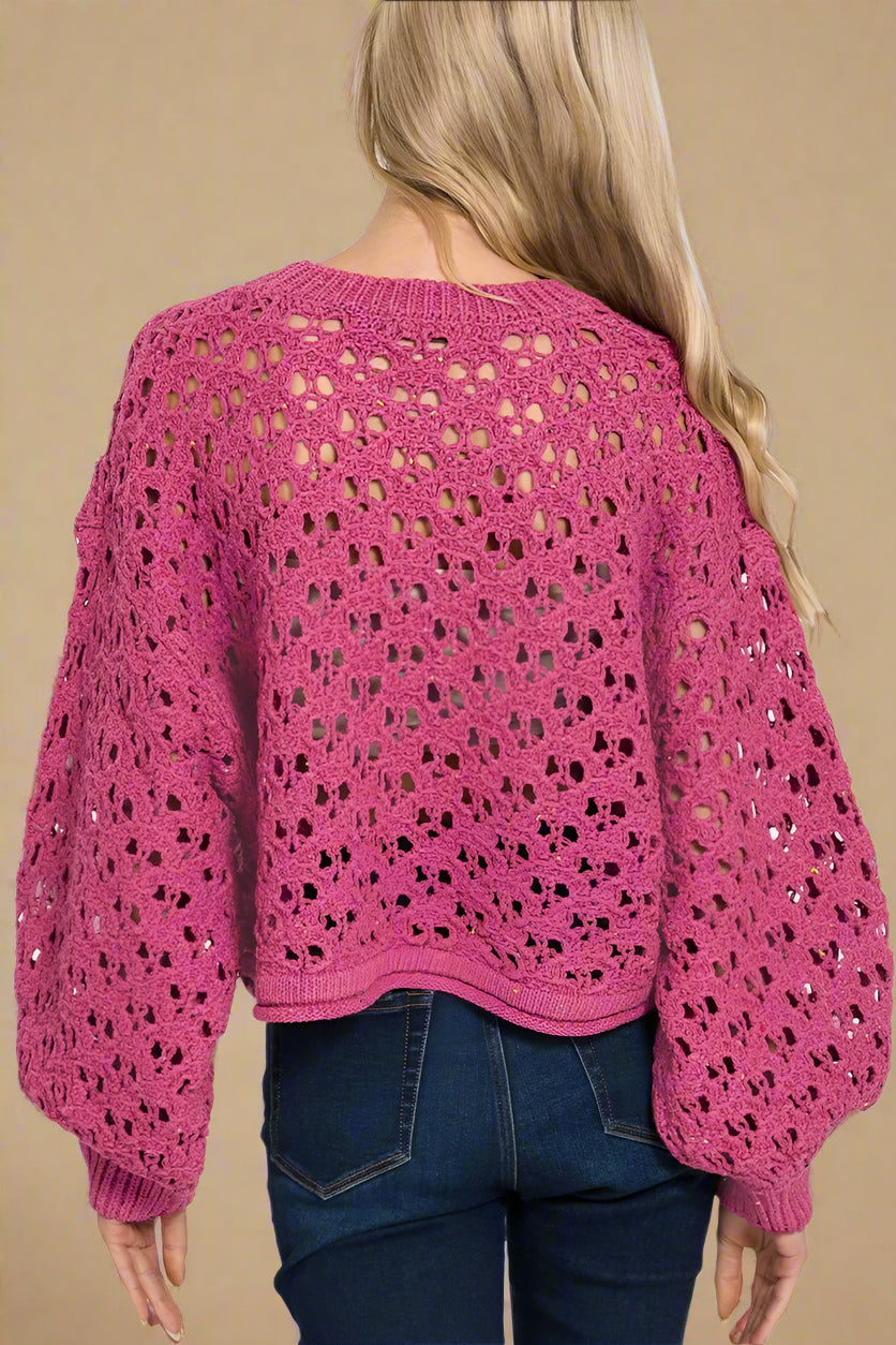 Pink crochet sweater worn by a person on a white background