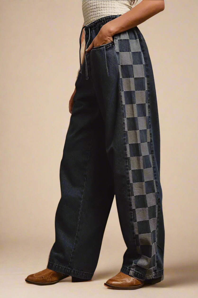 Person wearing wide-leg jeans with a checkered pattern on a plain background
