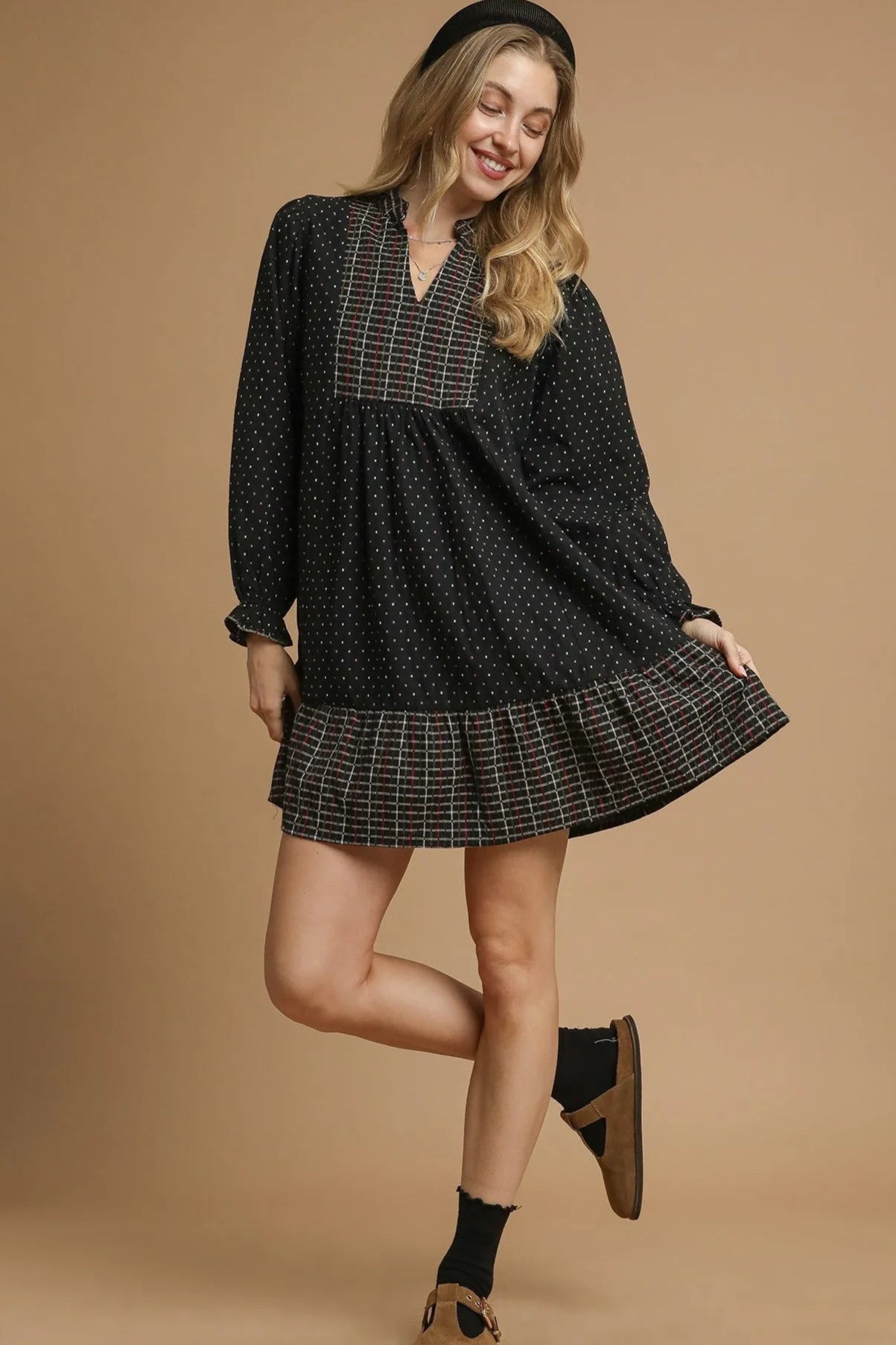 Woman wearing a black and plaid dress on a beige background