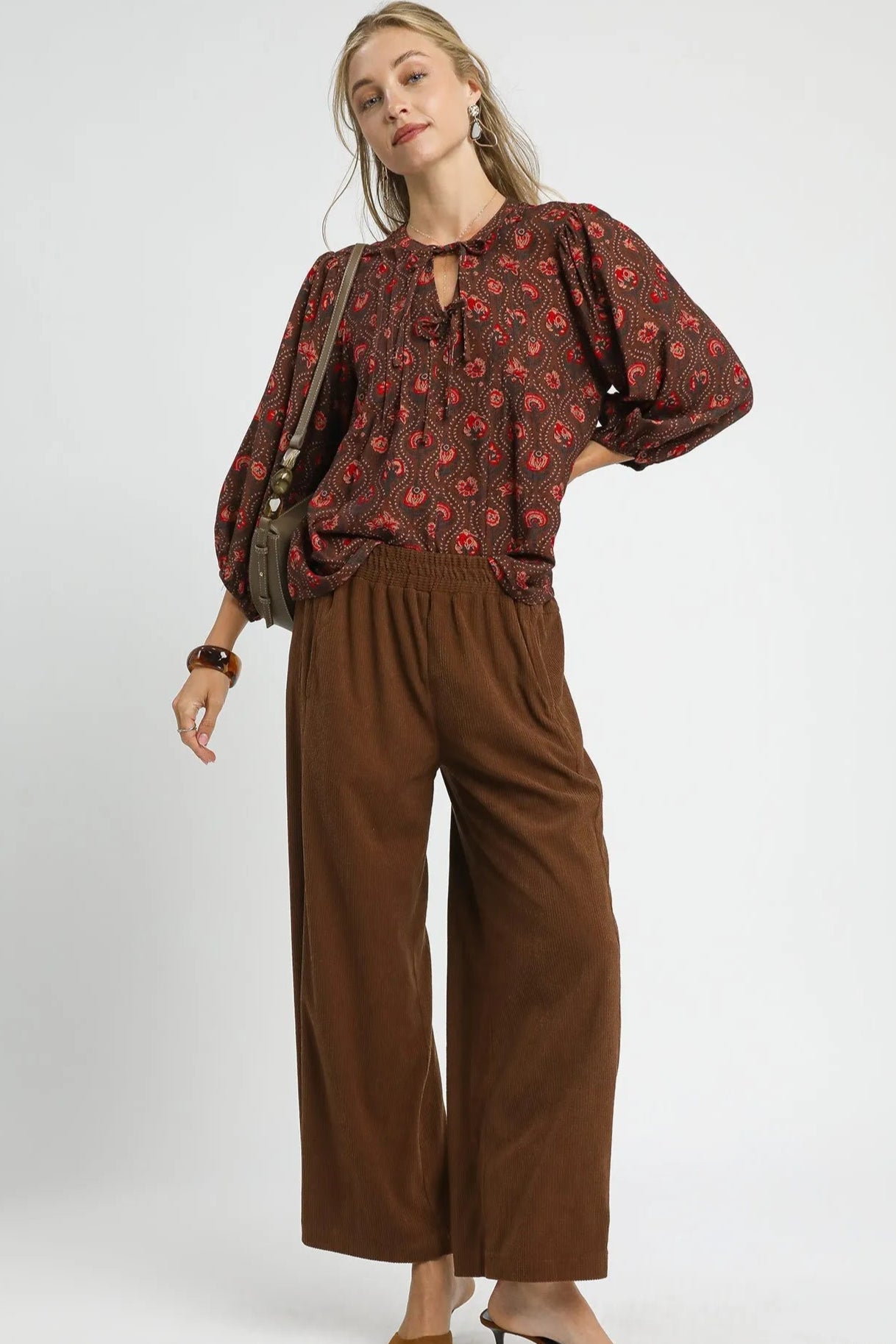 Woman wearing a brown floral blouse and brown pants on a white background