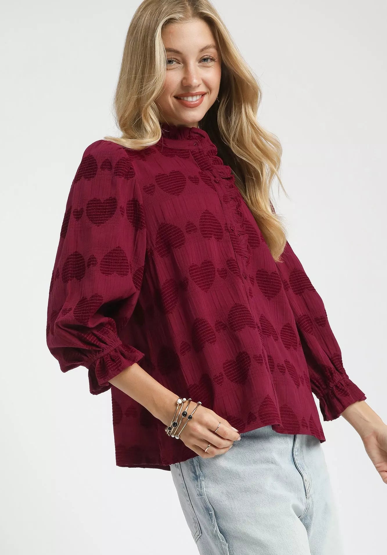 Woman wearing a burgundy blouse with heart patterns on a white background