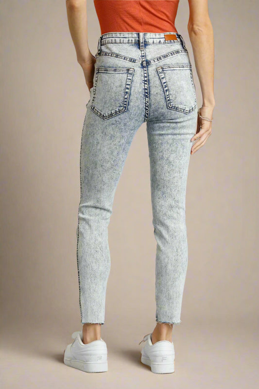 Light denim jeans worn by a person on a beige background