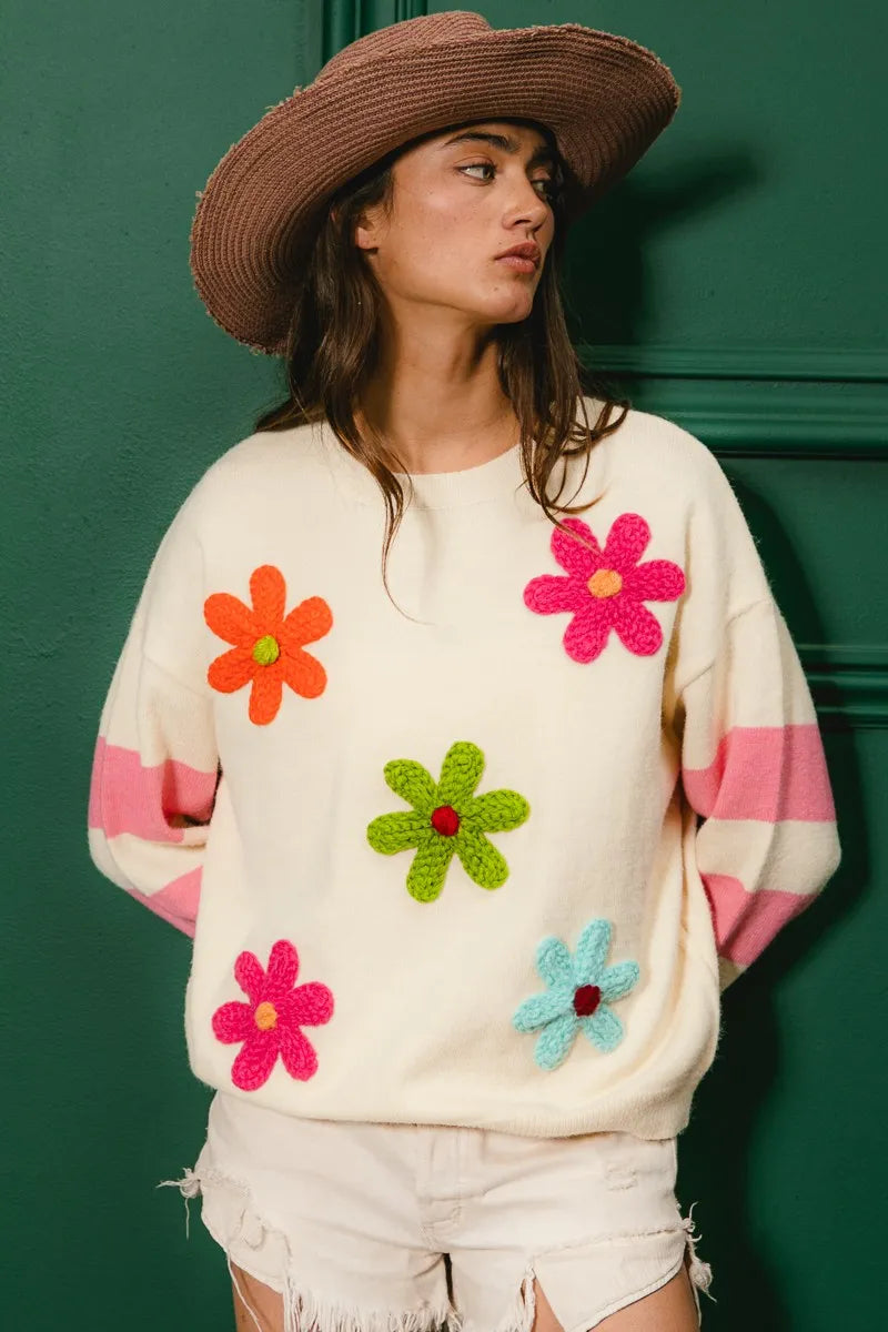 Woman wearing a sweater with colorful flower patterns against a green background