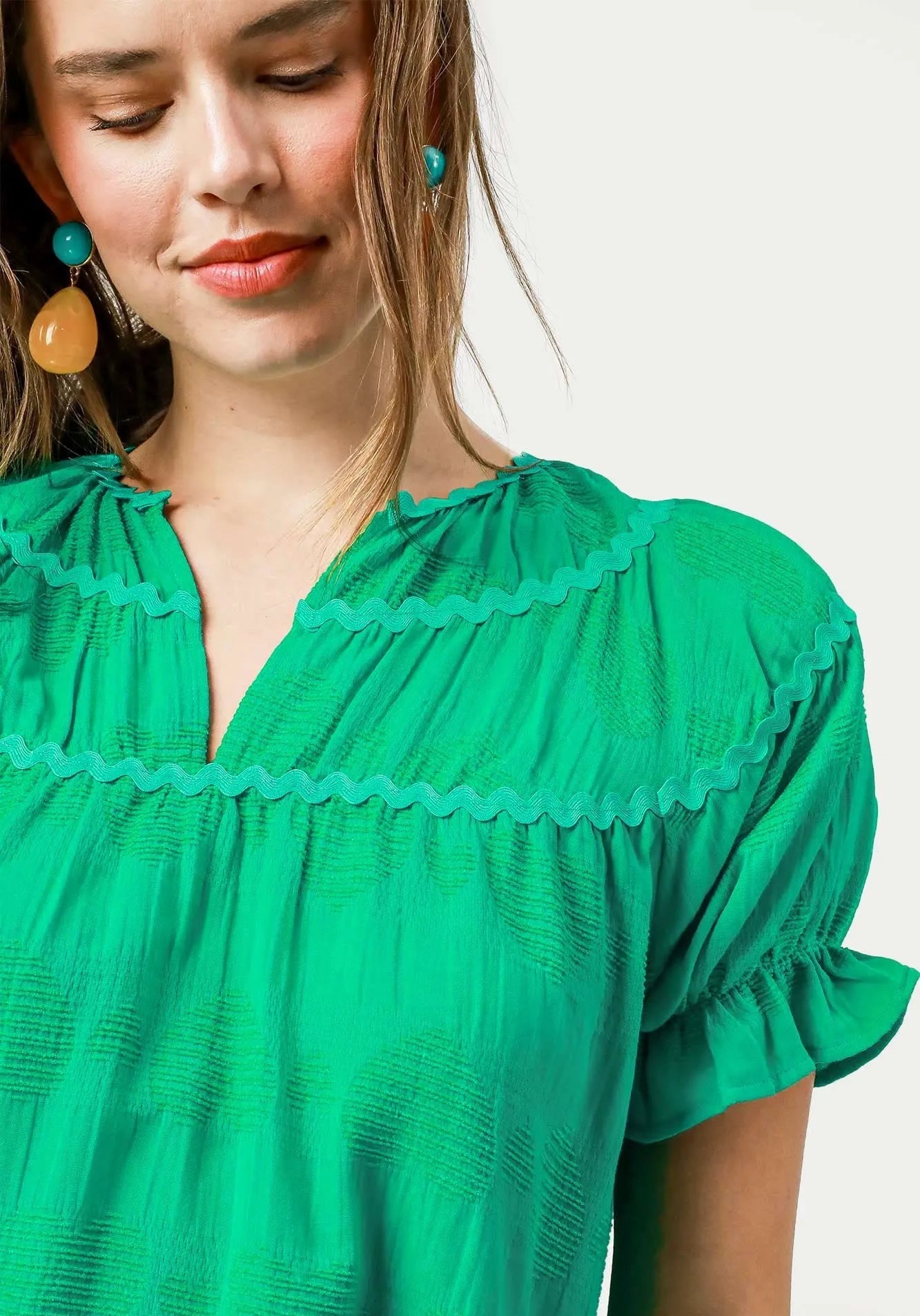 Woman wearing a green blouse with ruffled details on a white background