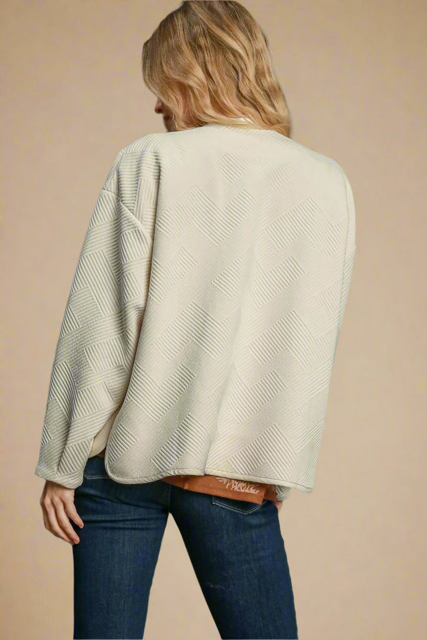 Person wearing a cream sweater and blue jeans on a beige background