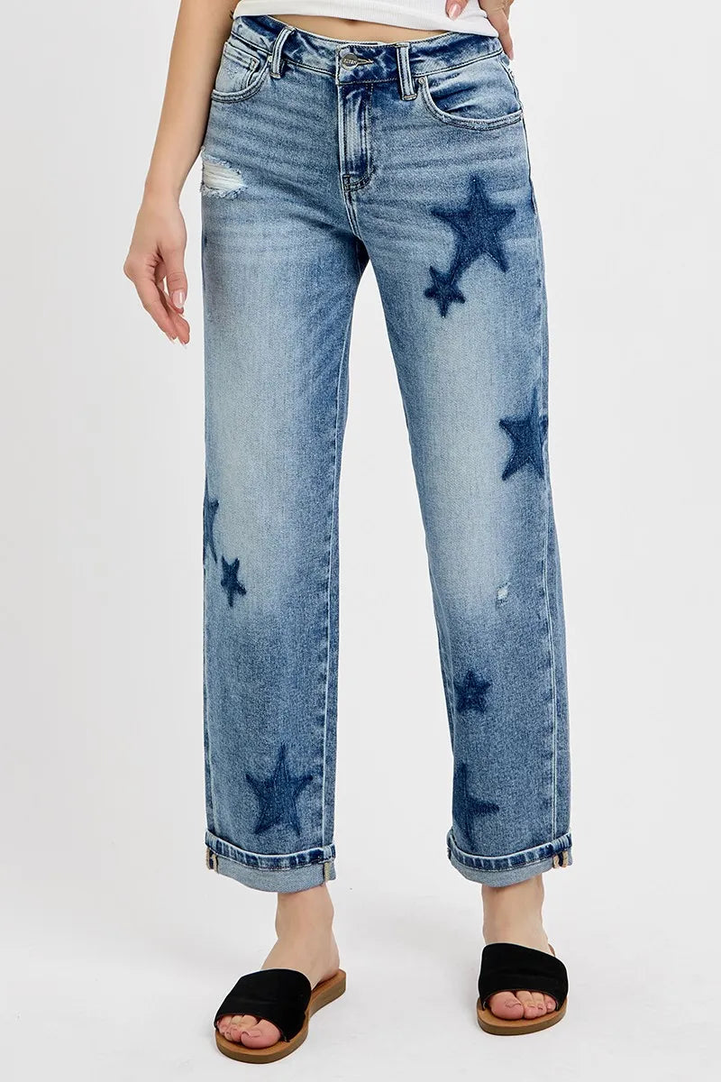 Blue jeans with star patterns worn by a person on a white background