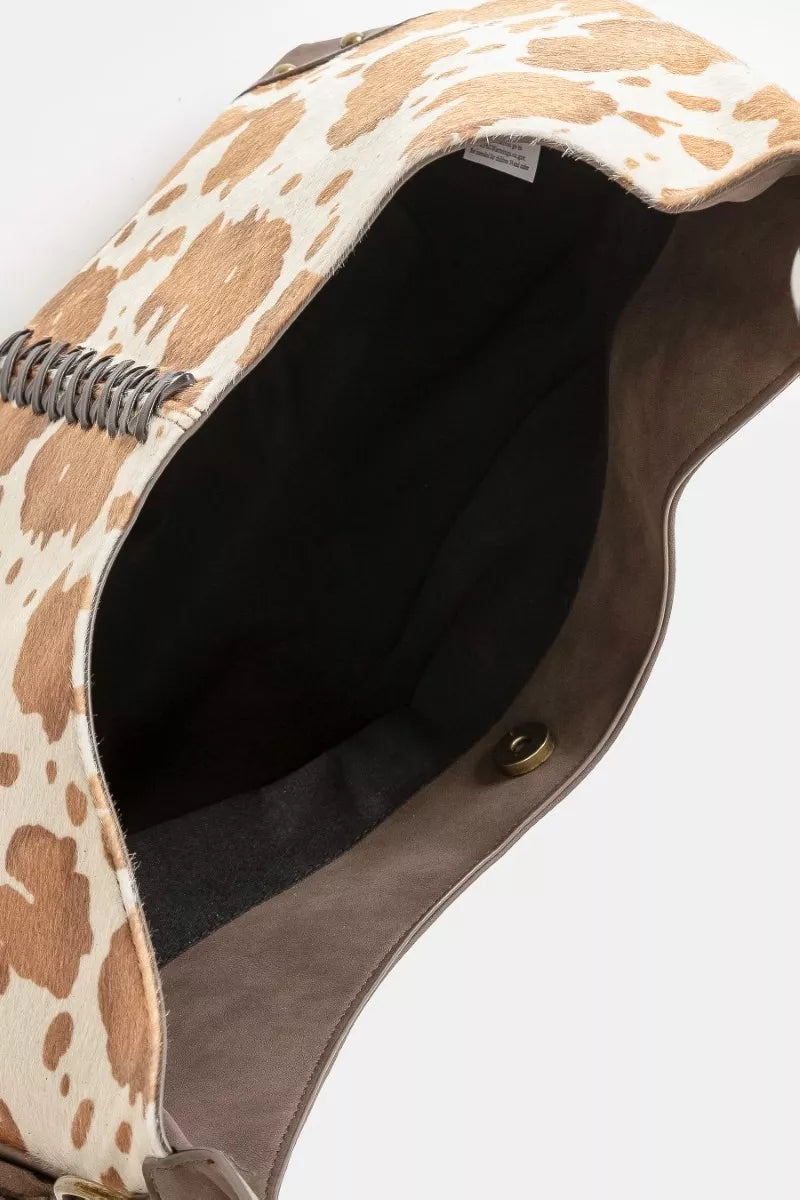 Close-up of a cow print handbag with a white background