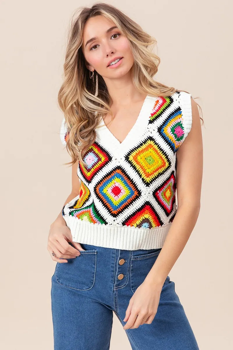 Woman wearing a colorful patterned sleeveless sweater against a beige background