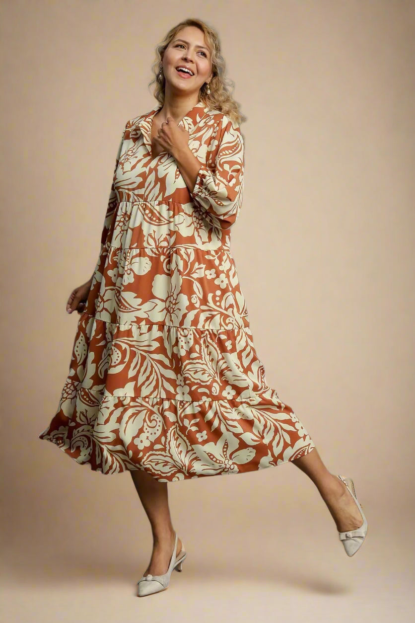 Woman wearing a rust-colored floral dress on a gray background