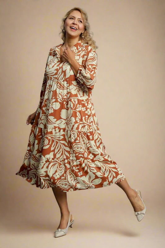 Woman wearing a rust-colored floral dress on a gray background
