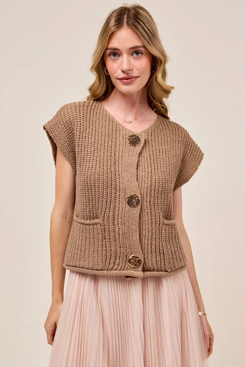 Woman wearing a brown knitted vest with buttons on a beige background