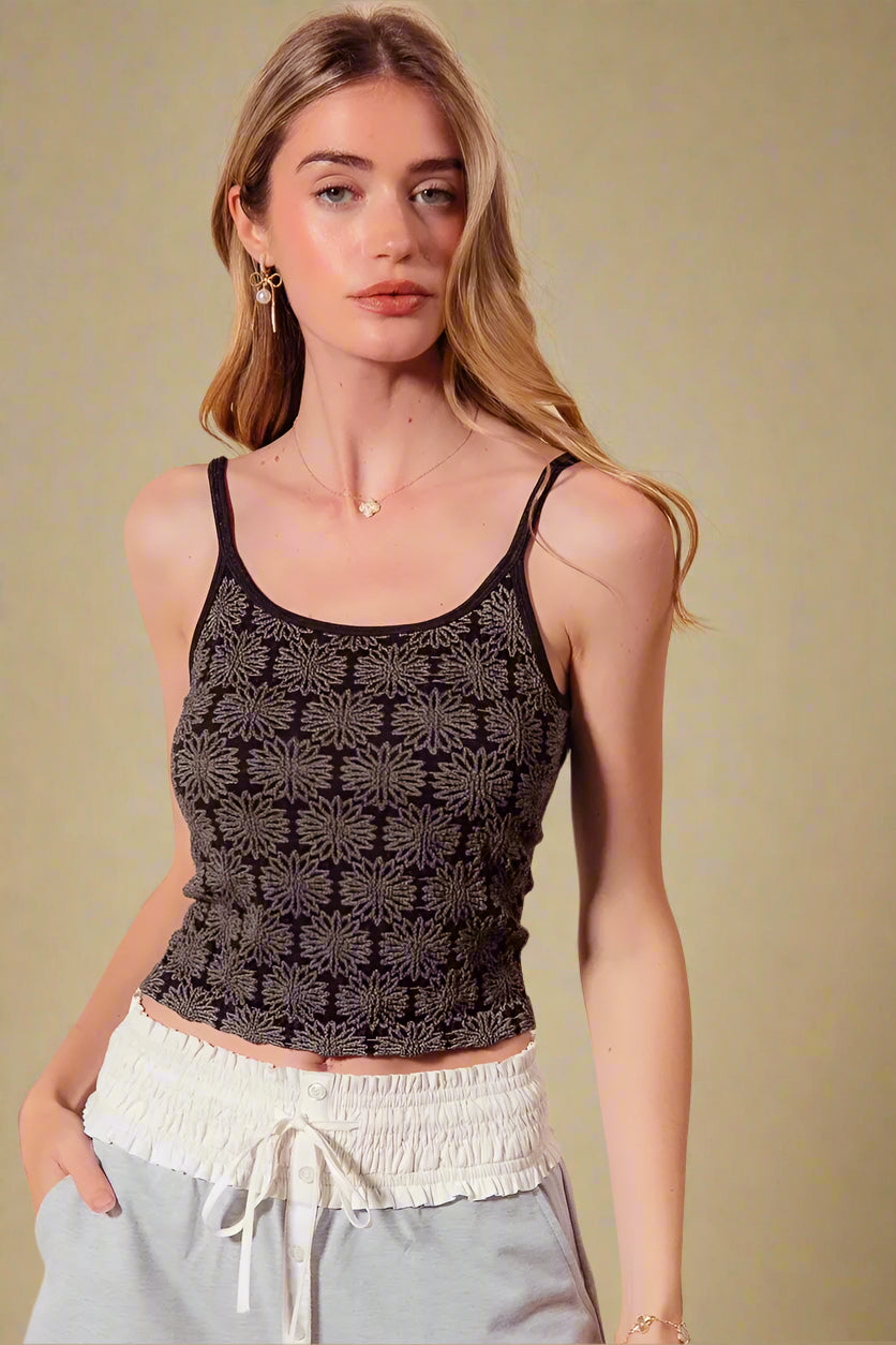 Woman wearing a black patterned tank top against a beige background