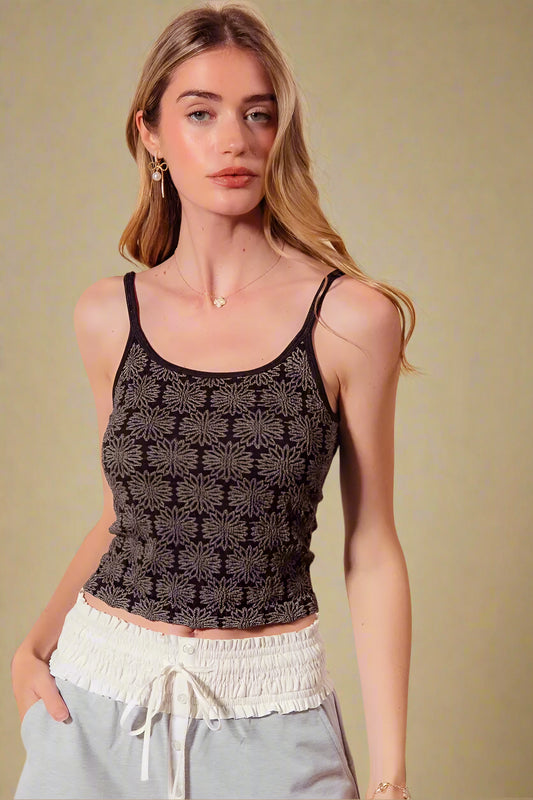 Woman wearing a black patterned tank top against a beige background