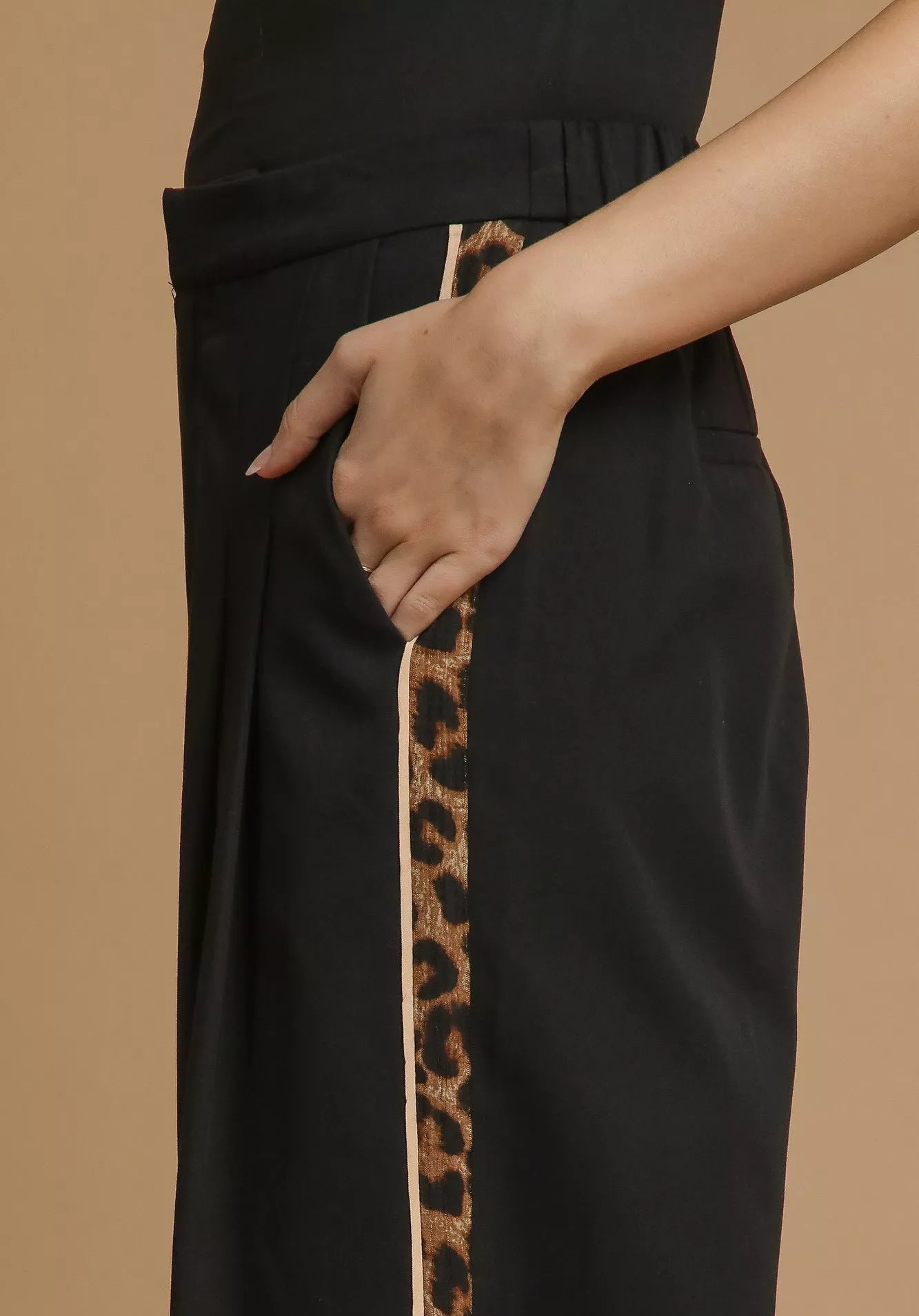 Black pants with a leopard print trim on a beige background