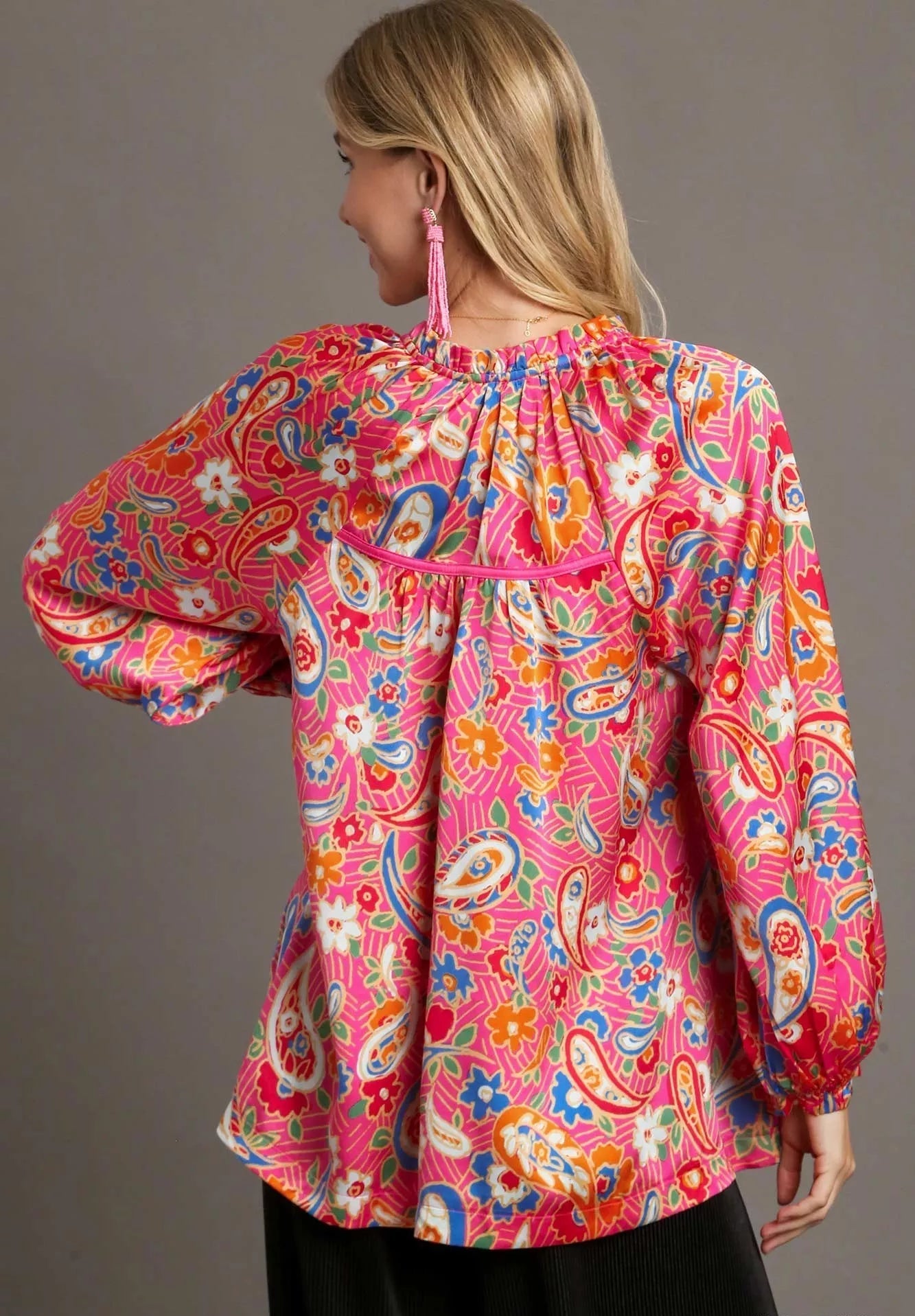 Woman wearing a colorful patterned blouse with a plain background