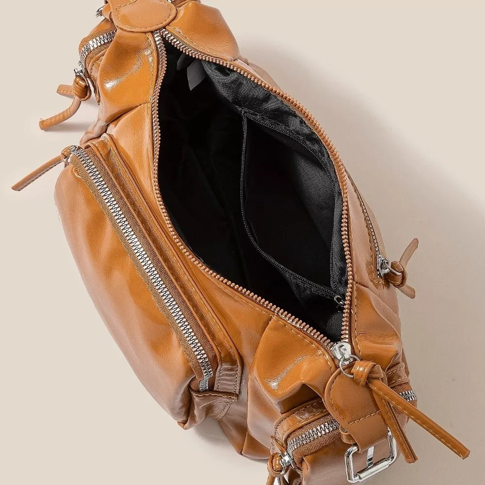 Brown leather bag with zippers on a beige background