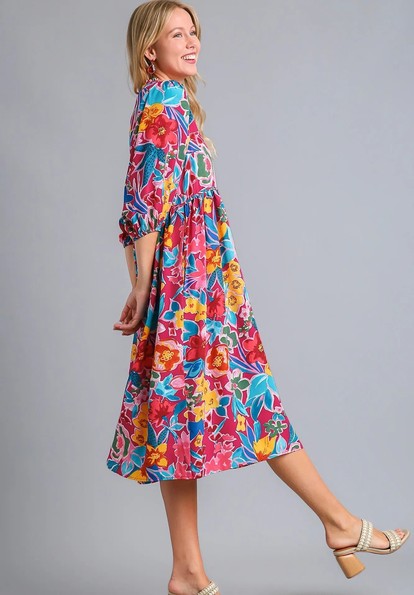 Woman wearing a colorful floral dress on a gray background