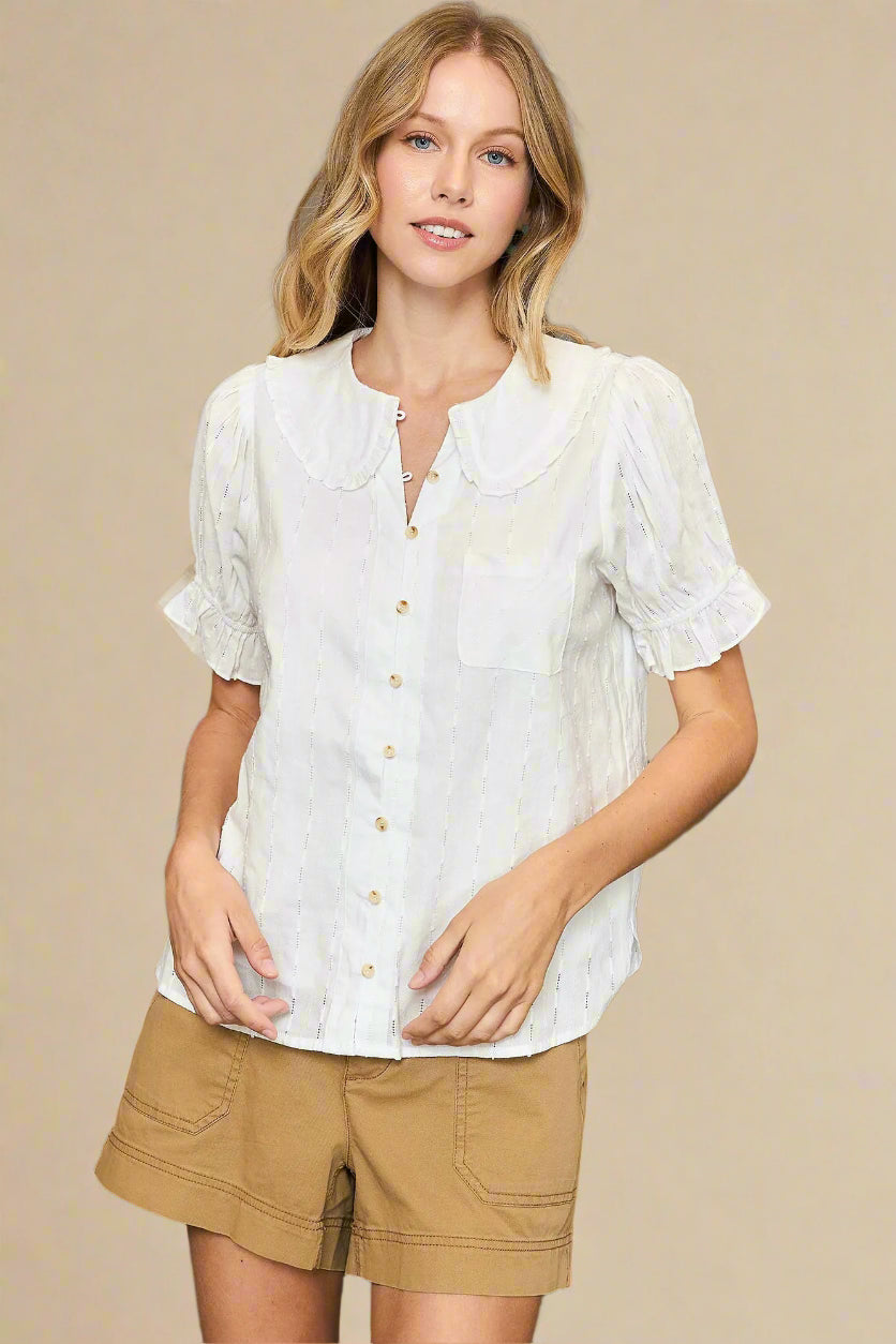 Woman wearing a white blouse and beige shorts against a beige background