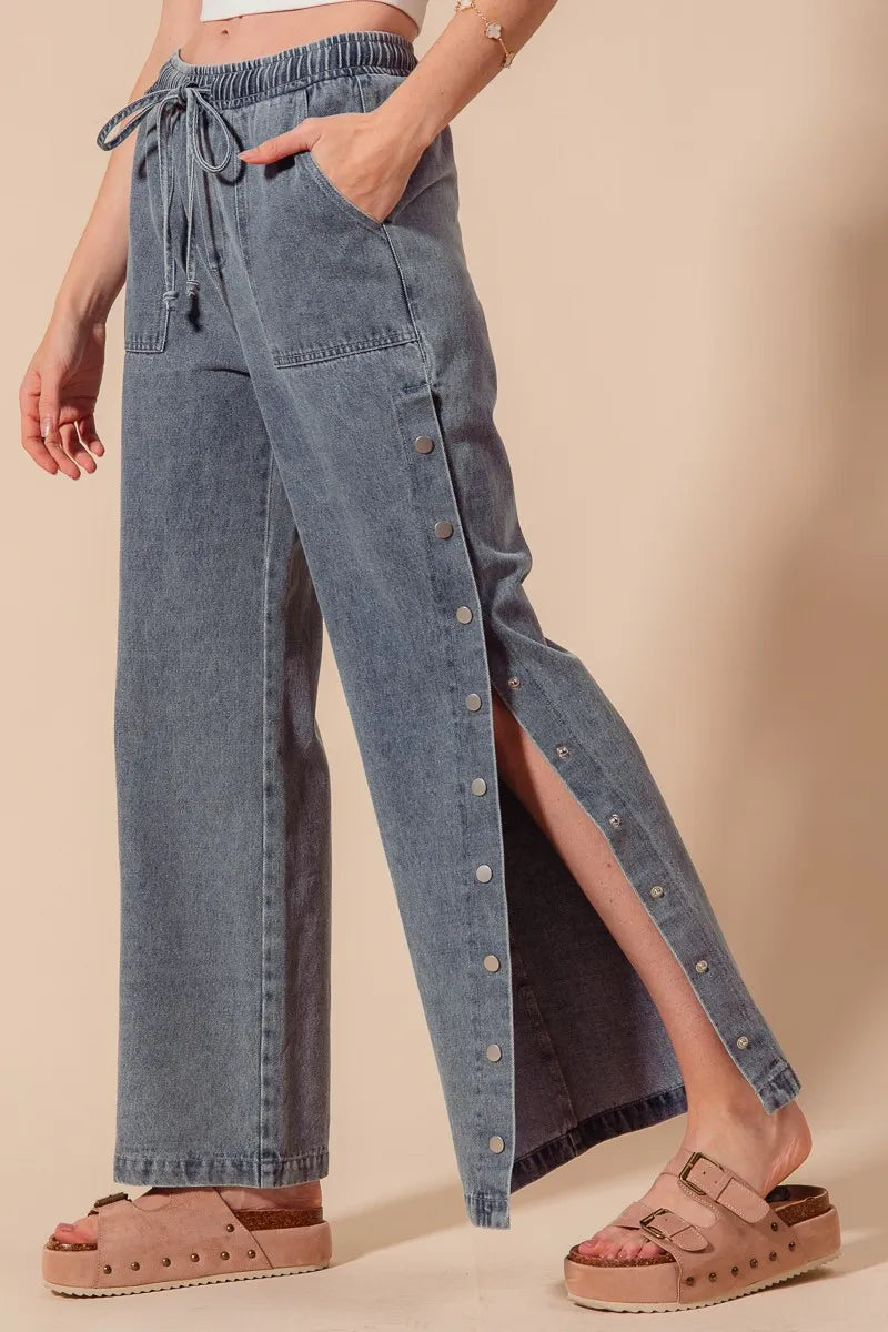Denim pants with a side slit worn by a person on a beige background