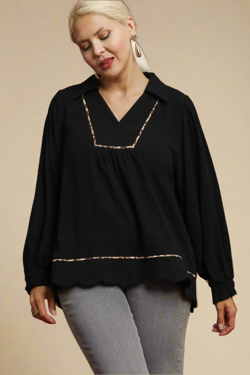 Woman wearing a black blouse with leopard trim on a beige background