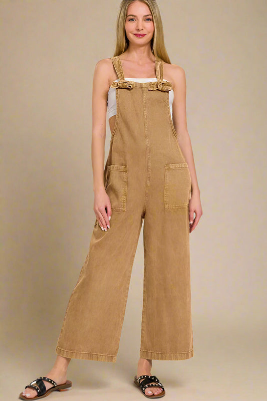 Woman wearing a deep camel colored overalls on a white background