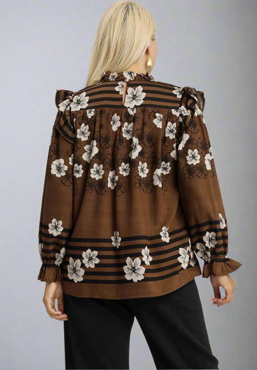 Woman wearing a brown floral blouse with black stripes on a white background