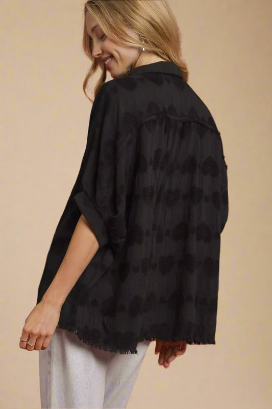 Woman wearing a black patterned shirt against a red background